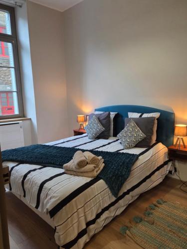 a bedroom with a bed with a blue headboard and pillows at La Pause Dinannaise in Dinan