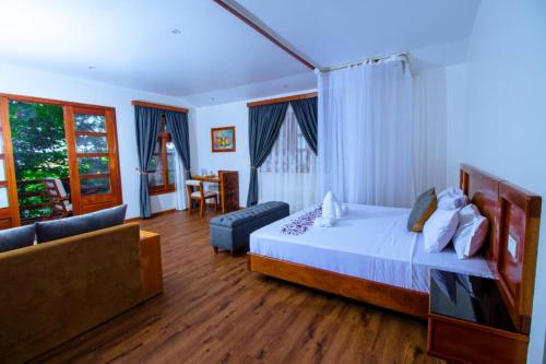 a bedroom with a bed and a couch in a room at Across The Nile Resort Jinja in Njeru
