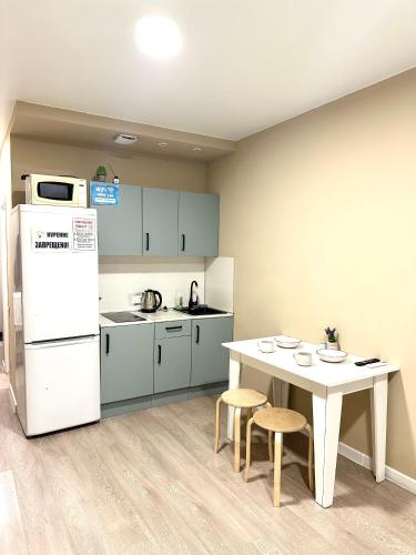 Una cocina con una mesa y un refrigerador blanco. en River Time 148, en Almaty