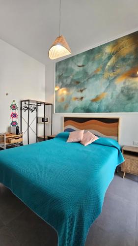 a bedroom with a blue bed with a painting on the wall at Thai Boutique rooms in Peschici