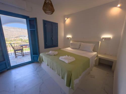 a bedroom with a bed and a balcony with a view at Amorgona Apartments in Katapola