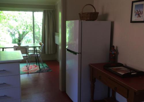 a kitchen with a white refrigerator and a table at Kookaburra Cottage in Castlemaine