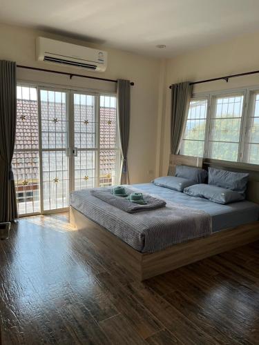 a bedroom with a large bed with windows at baan wongsupar in Suan Phung