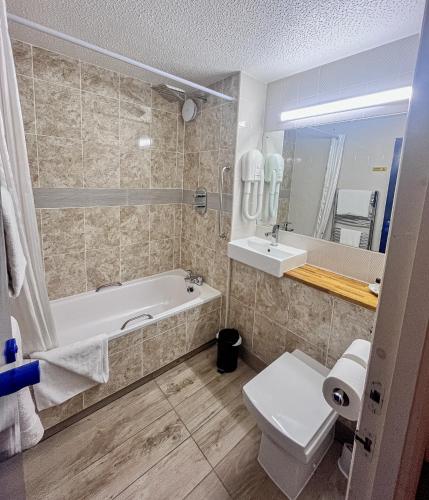a bathroom with a tub and a toilet and a sink at Travel Plaza Hotel in Desborough