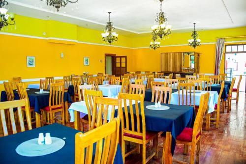 a dining room with blue tables and chairs and yellow walls at Umzimkulu Hotel in Umzimkulu