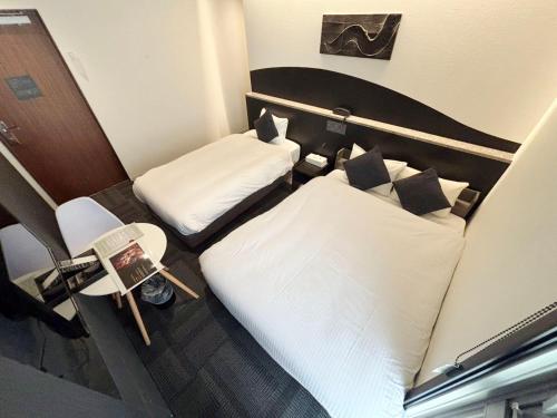 a hotel room with two beds and a chair at Seiei Hotel Kyoto Kawaramachi in Kyoto