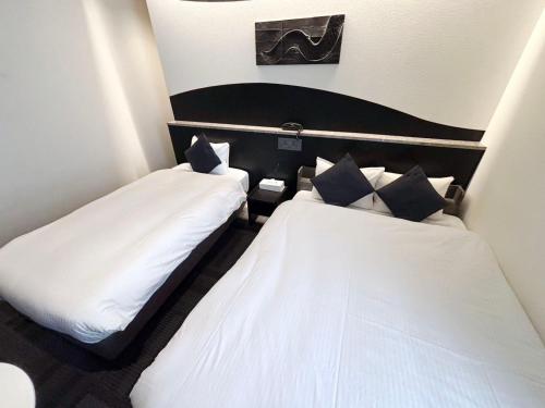 two beds in a small room with white sheets at Seiei Hotel Kyoto Kawaramachi in Kyoto