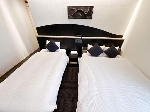 two beds sitting next to each other in a room at Seiei Hotel Kyoto Kawaramachi in Kyoto