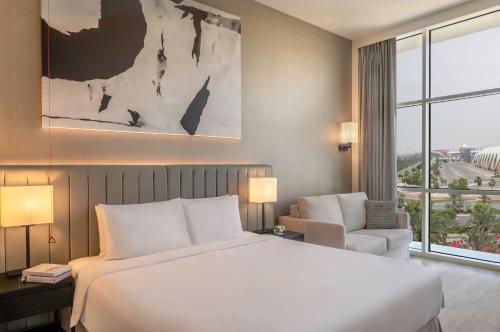 a bedroom with a large white bed and a chair at Yas Plaza Marina by IHG in Abu Dhabi