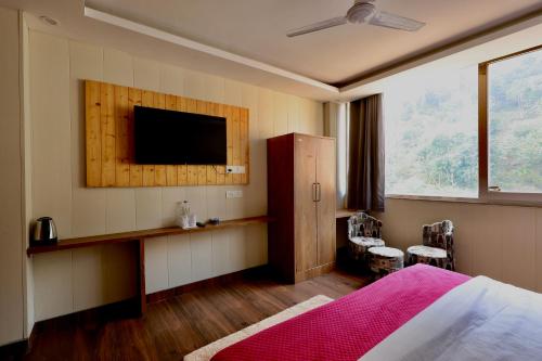 a bedroom with a bed and a flat screen tv at Sufi stay in Rishīkesh