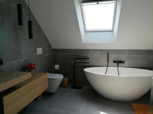 a bathroom with a large white tub and a window at LE CLOS DU MONTYS in Louveigné