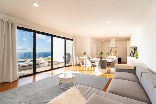 a living room with a couch and a large window at GuestReady - The Ocean El Cid in Fajã da Ovelha