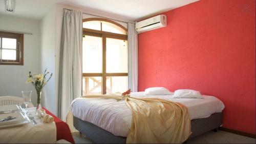 een slaapkamer met een rode muur en een bed bij Apartamento em Residencial Riviera in Florianópolis
