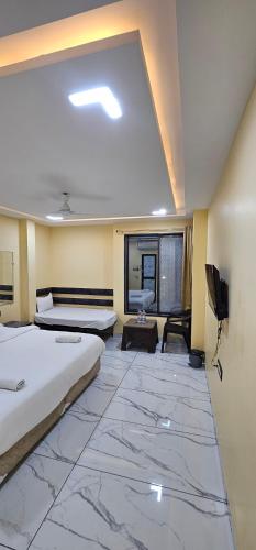 a large room with two beds and a tv at Hotel Roshan in Ujjain