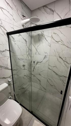 a bathroom with a glass shower with a toilet at Chalés Boqueirão beach in Japaratinga
