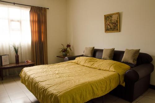 a bedroom with a bed with a yellow blanket on it at Hotel Plaza Real Suites & Apartments San Jose in San José