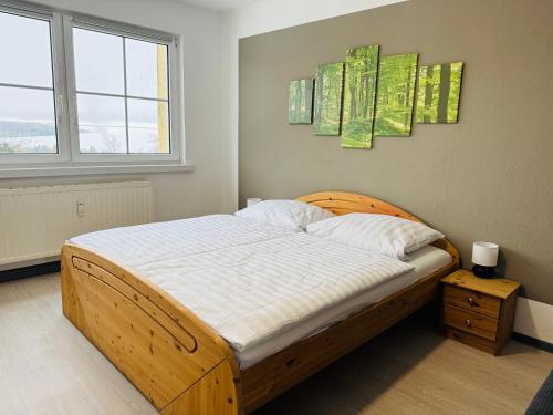 a bedroom with a bed with a wooden headboard and two windows at FeWo Einetal 4 im schönen Ostharz in Schielo