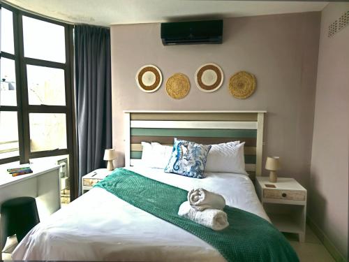 a bedroom with a bed with a teddy bear on a green blanket at Idwala Tides 14 Casablanca Tri-Story Apartment - Ballito in Ballito