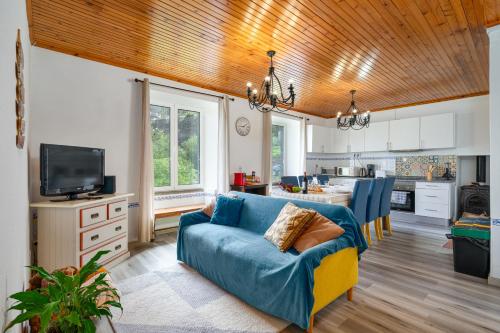 a living room with a blue couch and a kitchen at Gouveia Cottage in Seixal