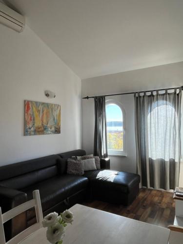 a living room with a black couch and a window at Villa Rosana in Rab