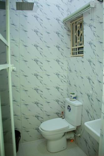 a white bathroom with a toilet and a window at Mbre Hotel and Resorts in Uyo