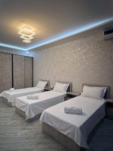 a hotel room with two beds with white sheets at ReveL HoteL in Tashkent