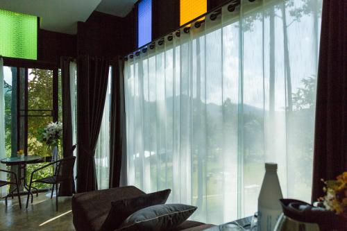 a living room with a large window with curtains at Phu Pha View Doi in Samoeng