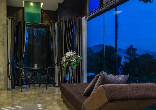 a living room with a couch and a large window at Phu Pha View Doi in Samoeng