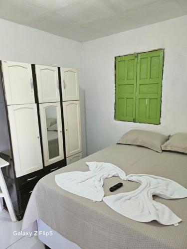 a bedroom with a bed with a green window at Pousada Tereza in Piranhas