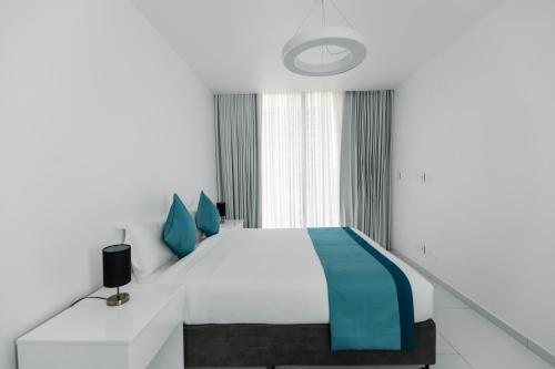 a bedroom with a white bed and blue pillows at Golf View Apartments in Maputo