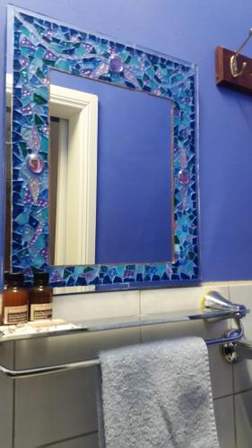 a bathroom with a mirror on a blue wall at Sonja's Bed and Breakfast in Lightning Ridge