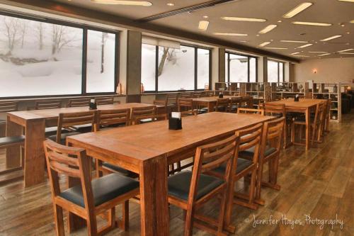 a restaurant with wooden tables and chairs and windows at Morino Lodge - Myoko in Myoko