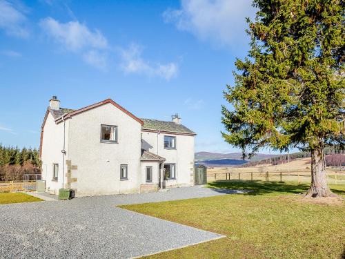 a white house with a tree in front of it at Knocknahighle in Cromdale