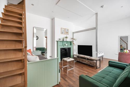 a living room with a green couch and a television at Berkeley Street Residences in London