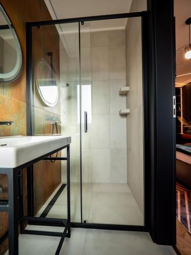 a glass shower in a bathroom with a sink at Premier Rooms in Szarvas