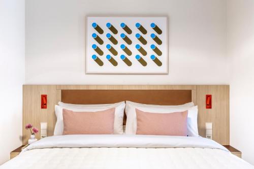 a bedroom with a white bed with pink pillows at Numa Madrid Fuencarral in Madrid