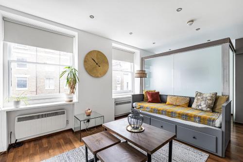 a living room with a couch and a clock on the wall at Berkeley Street Residences in London