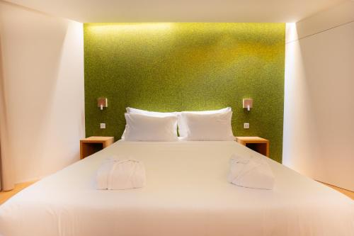 a bedroom with a large white bed with a green wall at Foz Côa Story House in Vila Nova de Foz Coa