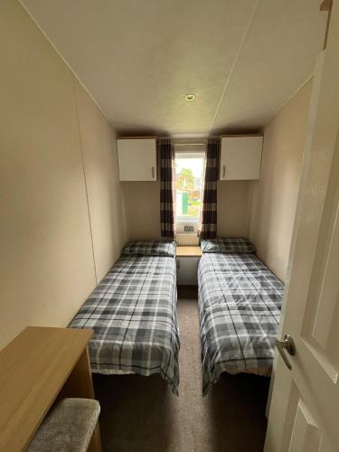 two beds in a small room with a window at Parkview Billing Aquadrome in Great Billing