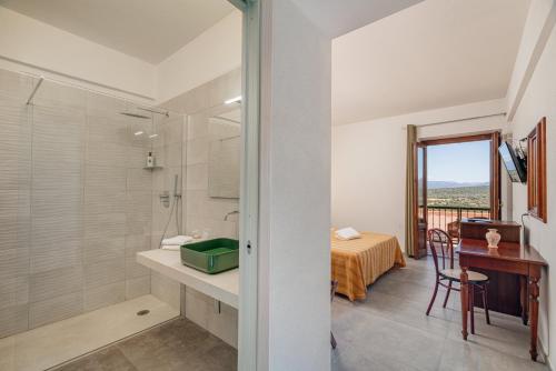 ein Badezimmer mit Dusche, Waschbecken und Schreibtisch in der Unterkunft Hotel Ispinigoli in Dorgali