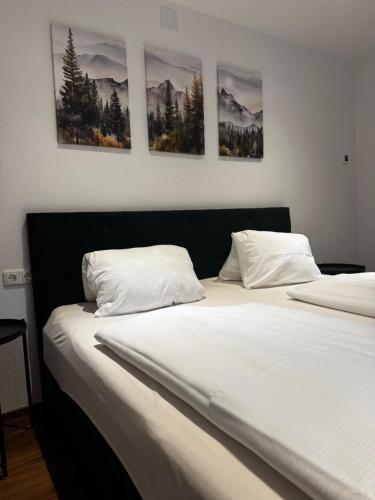 two beds in a bedroom with four pictures on the wall at Apartment Ramazotti - inklusive Eintritt in die Alpentherme in Bad Hofgastein