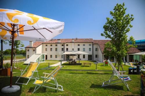 ein Park mit Stühlen und einem Sonnenschirm vor einem Gebäude in der Unterkunft Nomad Hostel in Treviso
