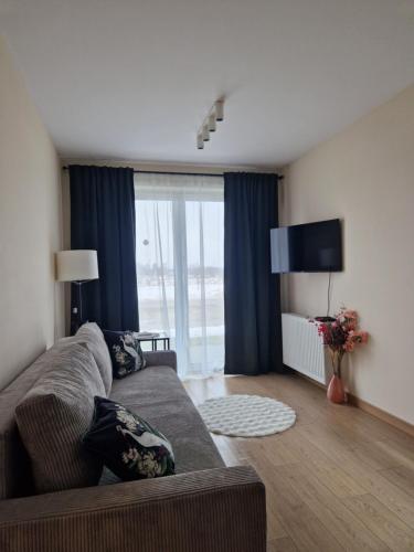 a living room with a couch and a large window at Apartament Potockiego Private Parking Faktura in Rzeszów