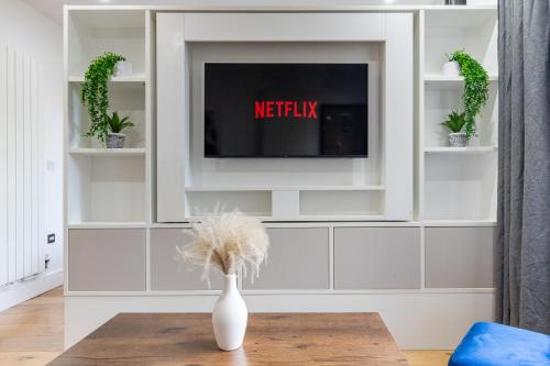 a living room with a tv and a vase on a table at Long Stay Close To Canary Wharf - Business Travelers, Contractors, Small Families in London