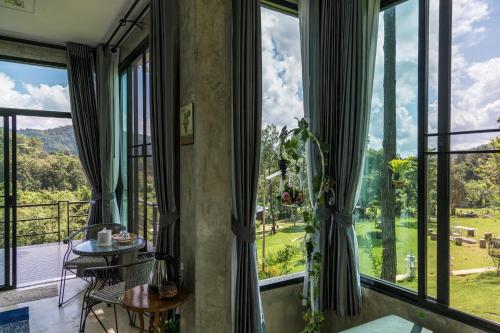 a room with large windows with a table and chairs at Phu Pha View Doi in Samoeng