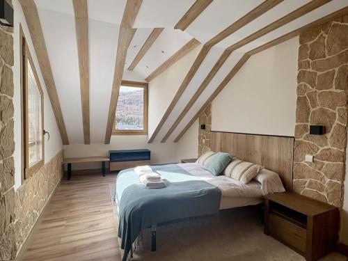 a bedroom with a bed and a stone wall at Atico de lujo en el Pirineo in El Pueyo de Jaca