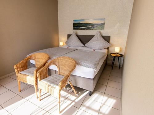 a bedroom with a bed with two wicker chairs at Romantischer Aufenthalt mit Blick auf den Weinberg in Kinheim