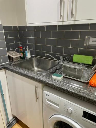 a kitchen counter with a sink and a dishwasher at York House Apartments in Romford