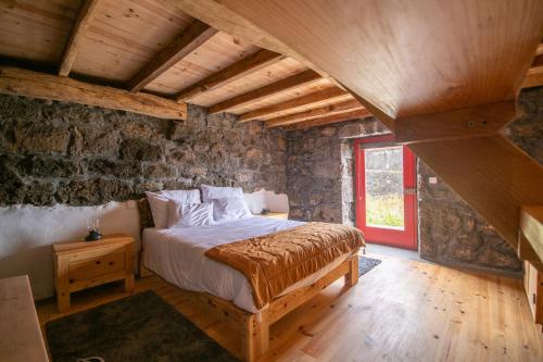 a bedroom with a bed in a room with stone walls at Ribeirinha 94 in Ribeirinha