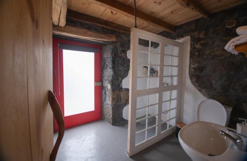 a bathroom with a red door and a sink at Ribeirinha 94 in Ribeirinha